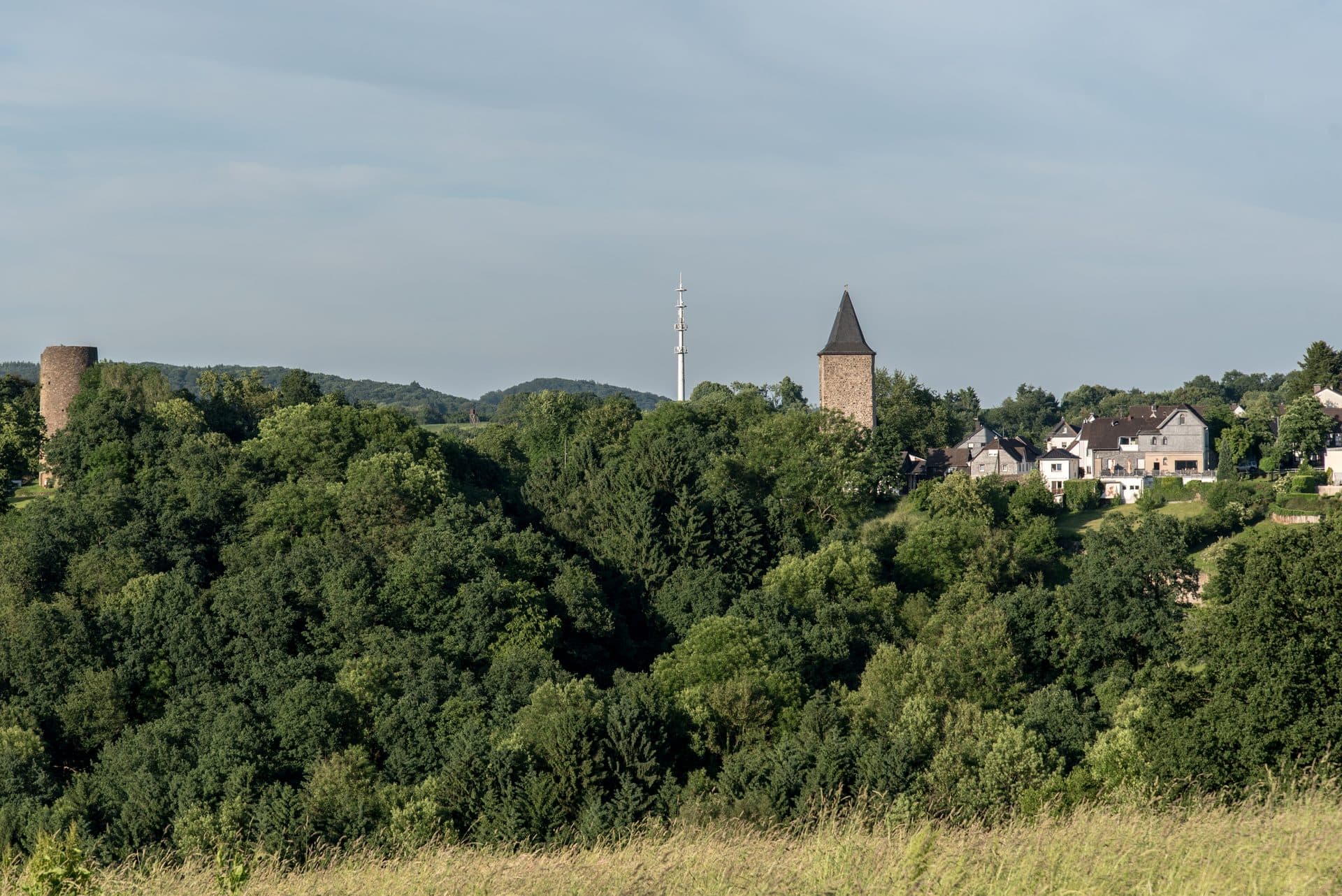 Stadt Blankenberg in Hennef, mittelalterliches Bergstädtchen mit dem Bergfried der Burgruine und dem Kirchturm über dem bewaldeten Siegtal